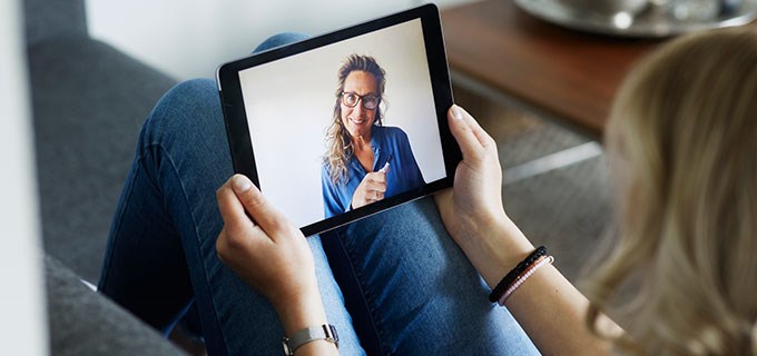 Person looking at a tablet with a video host on the screen