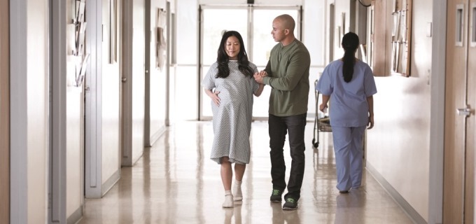 Pregnant woman, partner and doctor walking in a hospital hallway